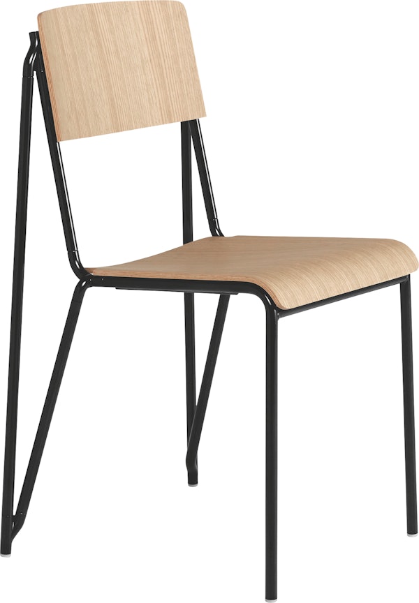 A three quarter side view of the Petit Standard Chair with oak seat and back, and black frame.